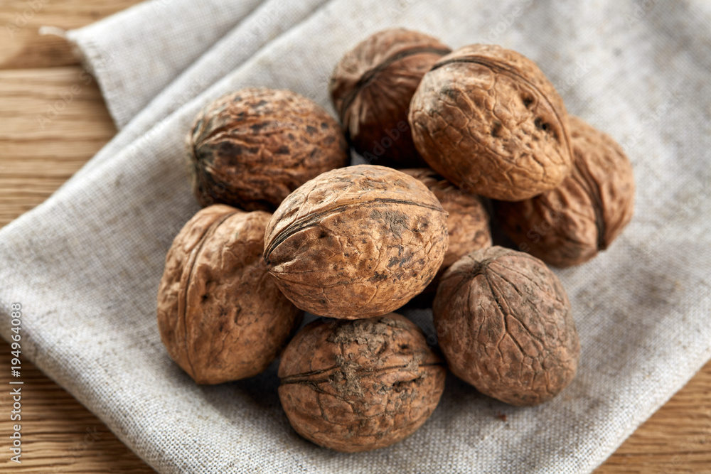 A stack of walnuts piled together and on rustic wooden background, shallow depth of field, selective focus A stack of walnuts piled together and on rustic wooden background, shallow depth of field, selective focus