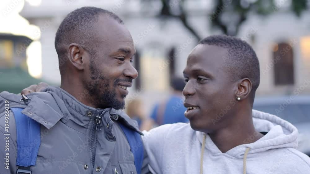 Two young black african friends talking and smiling in the street Two young black african friends talking and smiling in the street