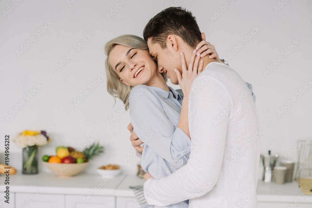 boyfriend hugging smiling girlfriend at kitchen boyfriend hugging smiling girlfriend at kitchen