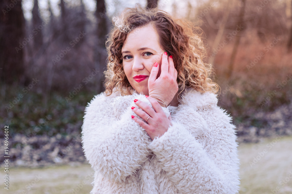 Outdoor close up portrait of beautiful curly woman wearing fur coat at park Outdoor close up portrait of beautiful curly woman wearing fur coat at park