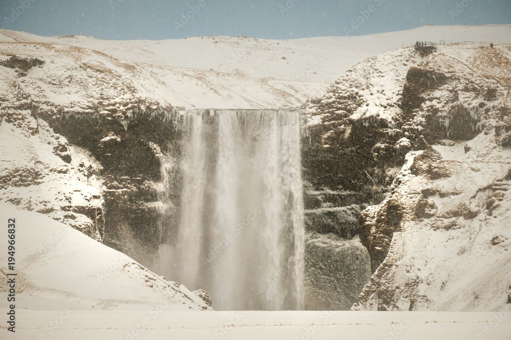 Fototapeta premium Skogafoss, the great and beautiful waterfall in Iceland during winter. Snow blizzard in Iceland near famous Skogafoss waterfall.