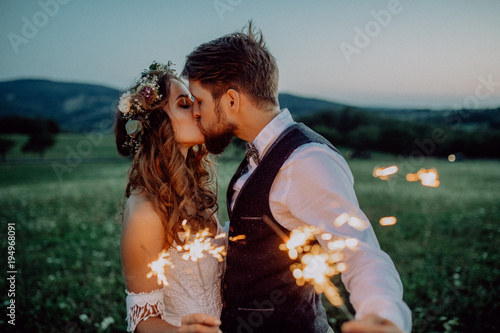 Beautiful bride and groom with sparklers on a meadow. photo