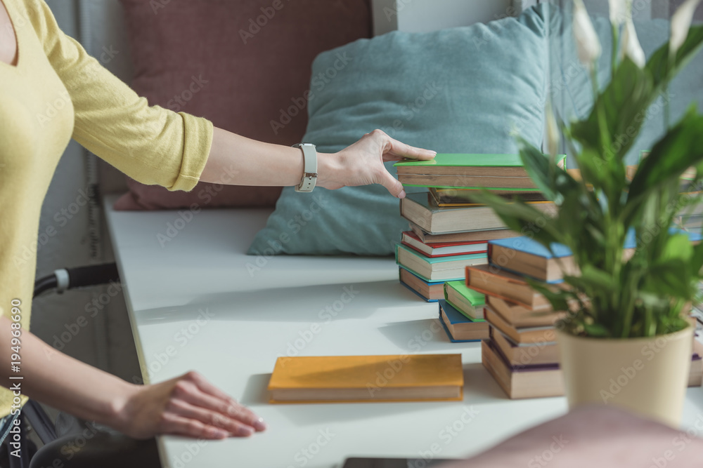 cropped image of woman taking book from stack on windowsill cropped image of woman taking book from stack on windowsill
