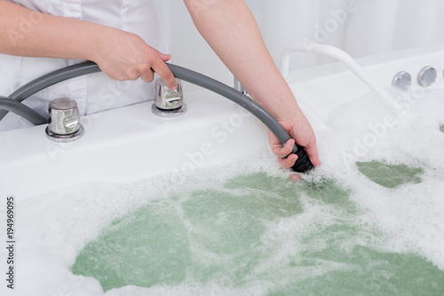 cropped shot of spa salon assistant regulating water in hydro bath