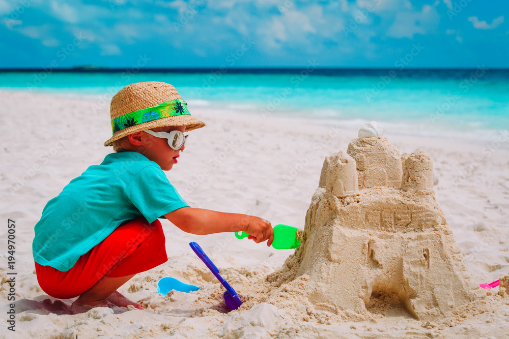 little boy building sand castle on beach little boy building sand castle on beach