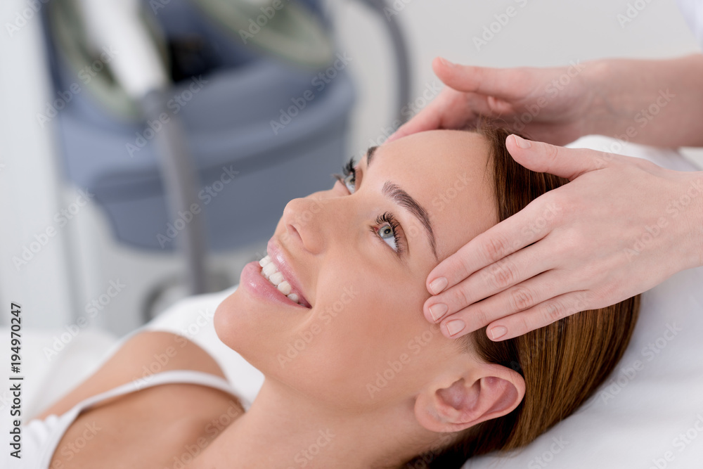 partial view of young woman getting head massage made by cosmetologist in salon