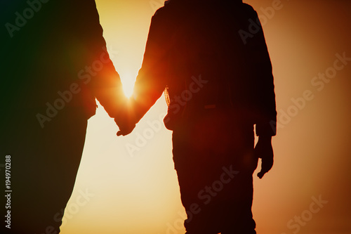 silhouette of parent and child holding hands at sunset