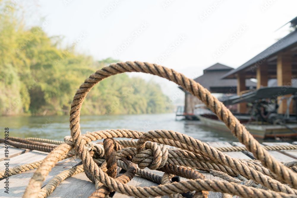Fototapeta premium closeup thick rope tie on the wooden terrace near river