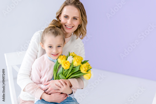 Hugging mother and daughter holding tulips for women's day