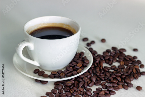 Black coffee in white glass and coffee beans placed on a white background.