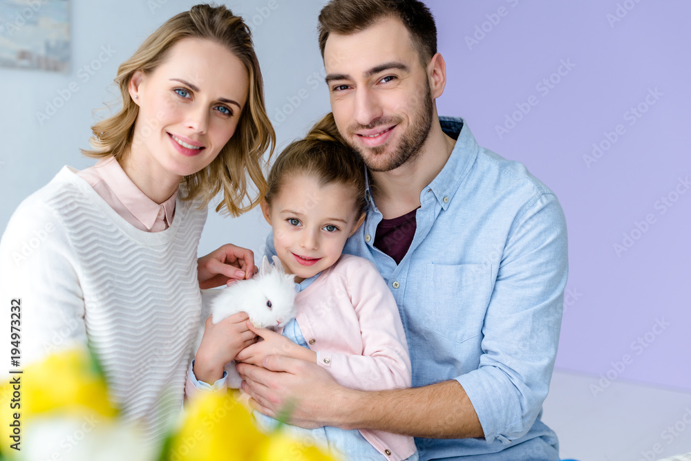 Happy family holding white rabbit