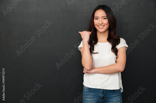 Smiling asian woman in t-shirt pointing away