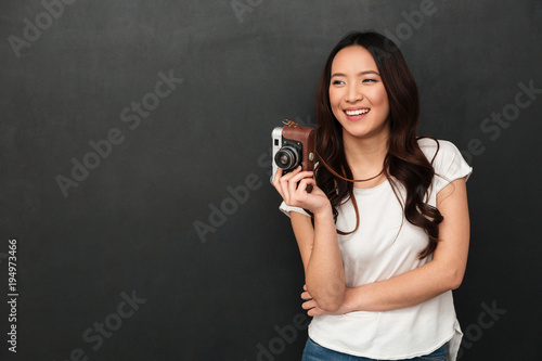 Cheerful asian woman in t-shirt holding retro camera