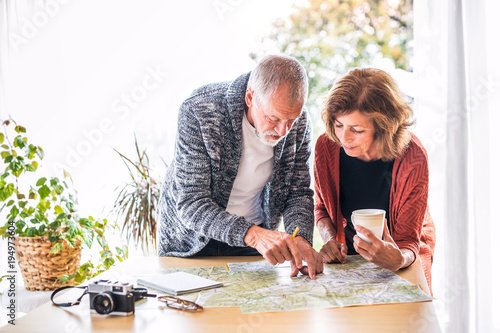 Senior couple with map at home, making plans. photo