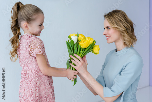 Child girl giving mother a bouquet of tulips on women's day