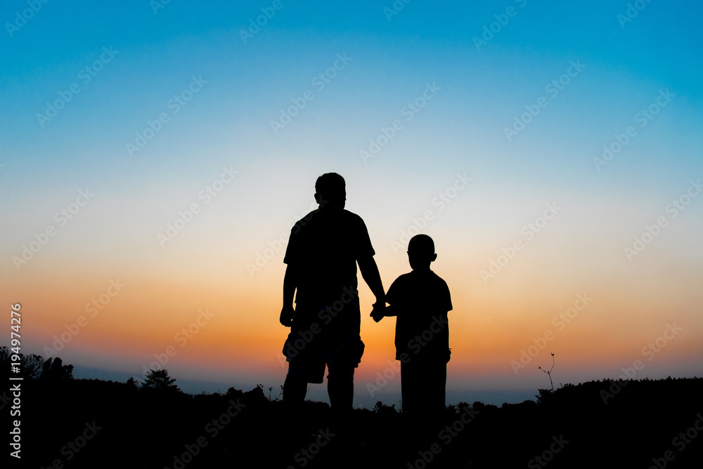 Silhouette Father and son hold hands in evening time