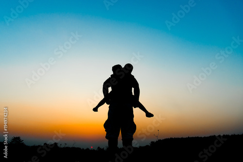 Silhouette the son is riding his father s neck.