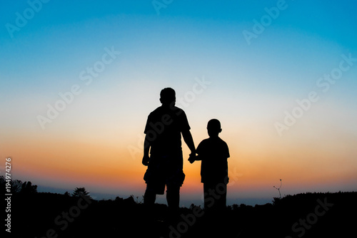 Silhouette Father and son hold hands in evening time