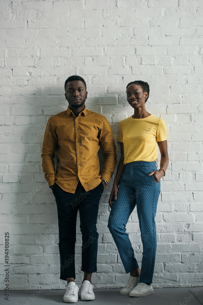 beautiful smiling young african american couple in yellow shirt and t-shirt looking at camera