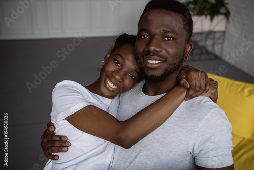 beautiful young african american couple embracing and smiling at camera