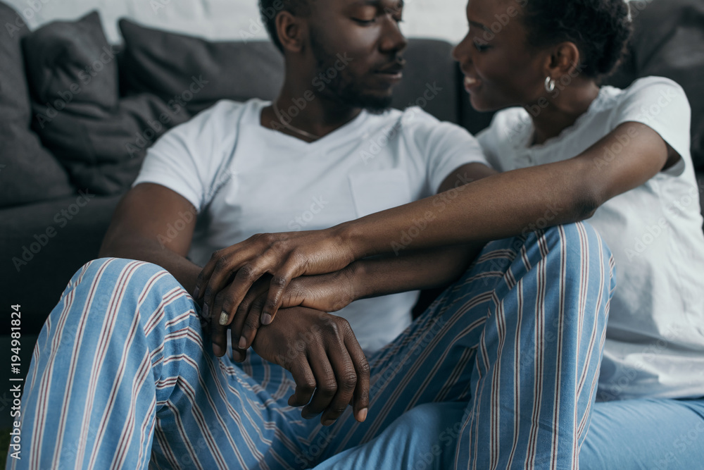 Fototapeta premium cropped shot of beautiful young african american couple in pajamas smiling each other at home
