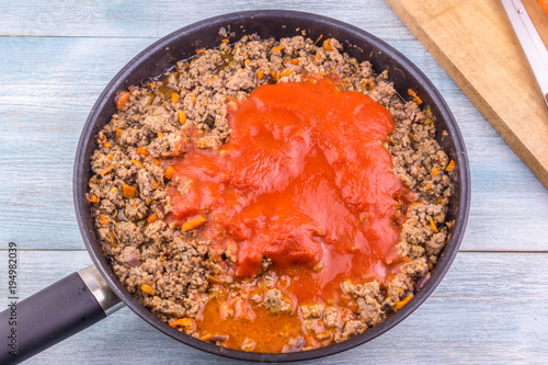Preparation of bolognese sauce - adding tomato paste to fried minced meat in a frying pan