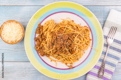 Spaghetti bolognese in a plate with a cup of grated Parmesan cheese