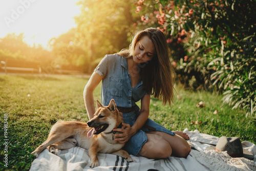 Beautiful young girl enjoying holidays in the park with her shiba inu dog, sunny weather, flare light effect
