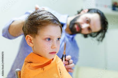 Child getting haircut at the hairdresser salon