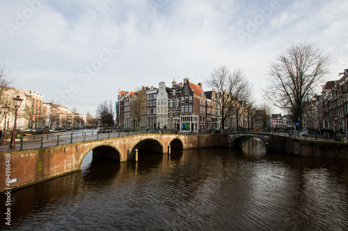Bridges and canal crossing in Amsterdam with houses overlooking the canal. Street system of the Dutch capital with bridges and canals. Typical view in Amsterdam