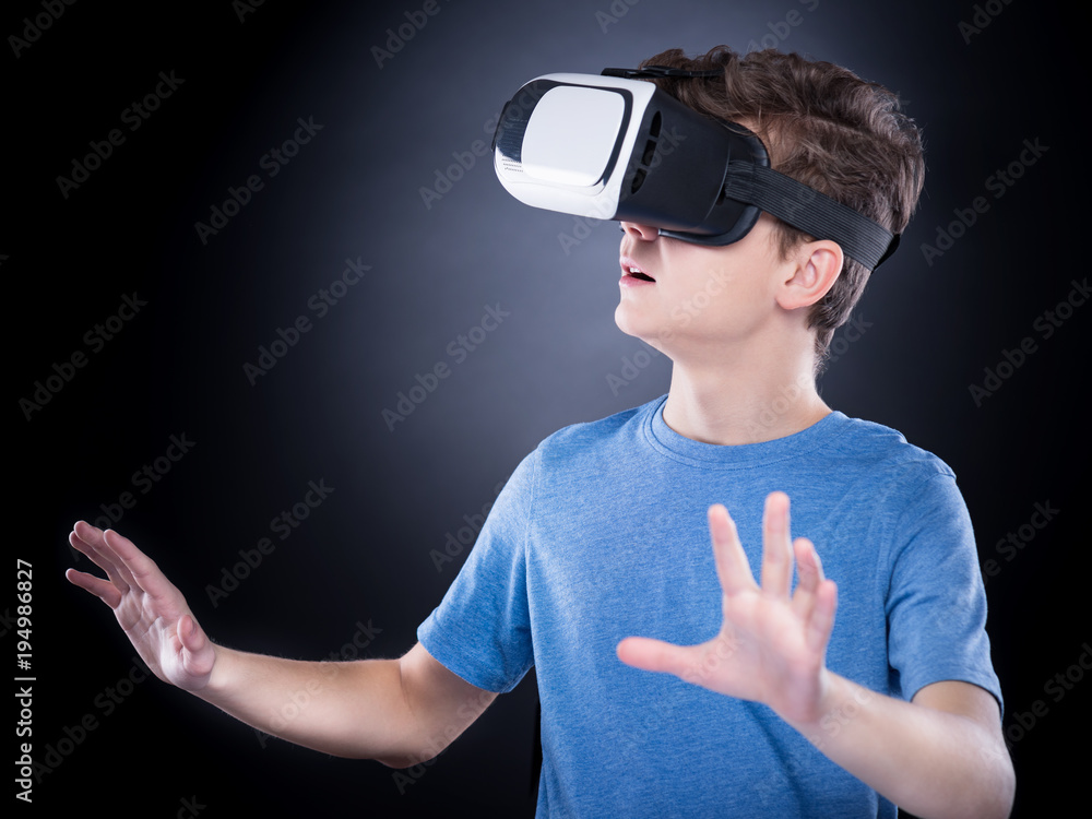 Happy teen boy wearing virtual reality goggles watching movies or playing  video games. Cheerful smiling teenager looking in VR glasses. Funny child  experiencing 3D gadget technology - close up. Stock Photo |