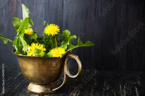Fototapeta Naklejka Na Ścianę i Meble -  Yellow dandelion flowers in a copper cup