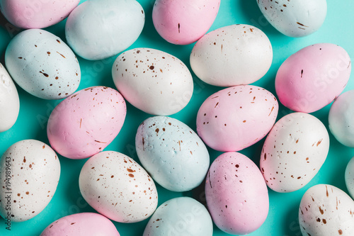 Bunch of colorful pastel eggs on blue background.