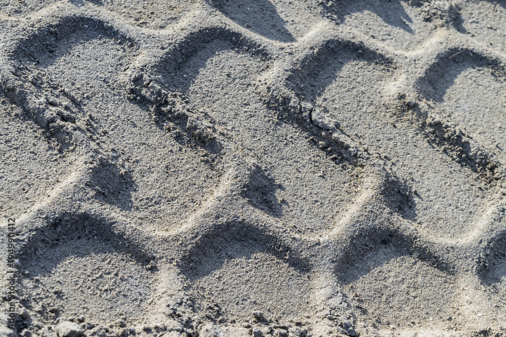 Traces on a dirt road. Impressions of wheels on the ground. Traces from the car's tire. Relief in the sand. Imprints in the sand. Interesting background. Natural texture Traces on a dirt road. Impressions of wheels on the ground. Traces from the car's tire. Relief in the sand. Imprints in the sand. Interesting background. Natural texture
