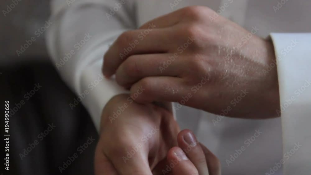 The young man fastens the sleeve of his shirt. The young man fastens the sleeve of his shirt.