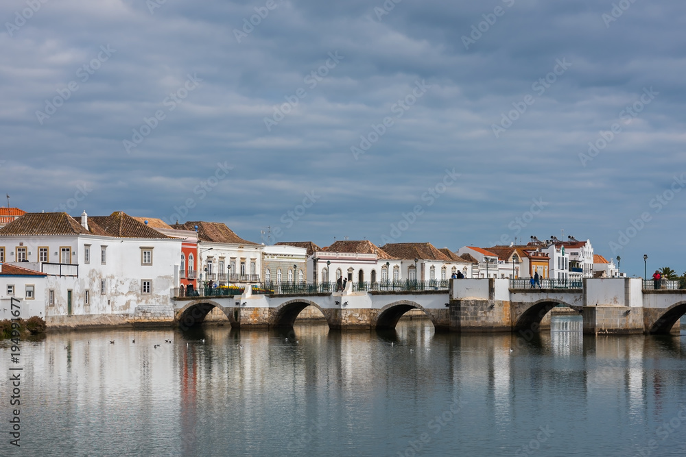 Roman bridge and historic buildings in the old center of Tavira on a cloudy day, Portugal