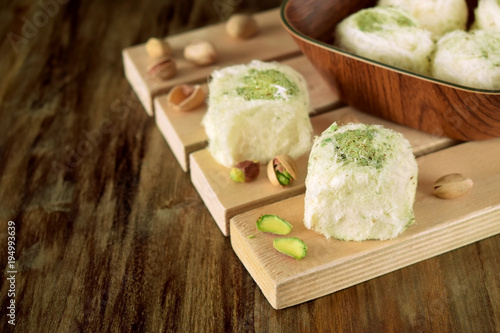 Turkish dessert. Cotton candy with pistachio on wooden boards surrounded by nuts photo