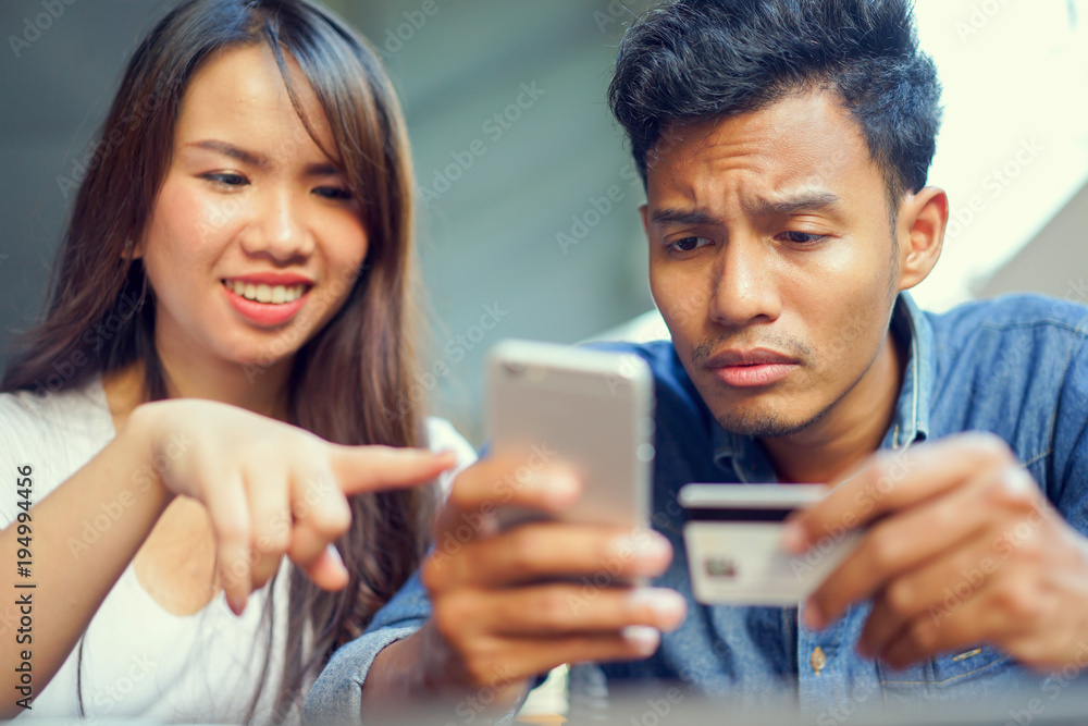 close up asian man using smartphone for payment by credit card and woman trying to help concept close up asian man using smartphone for payment by credit card and woman trying to help concept