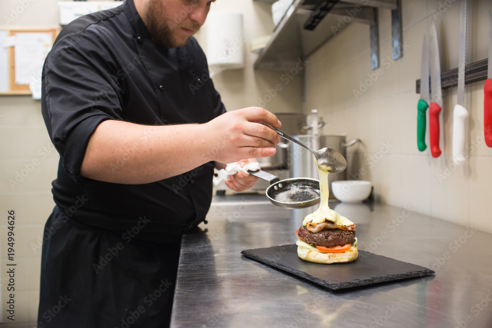 Cook putting sauce on burger Cook putting sauce on burger