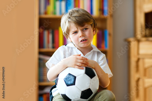 Sad and not happy little kid with football about lost football or soccer game. child after watching match on tv © Irina Schmidt