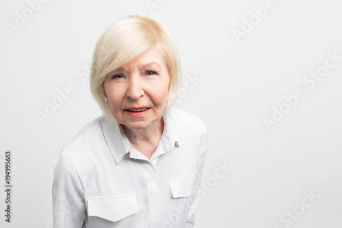 Old and tricky woman is very attentive to details. She is trying to check everything here. This grandma is very responcible and punctual. Close up. Isolated on white background