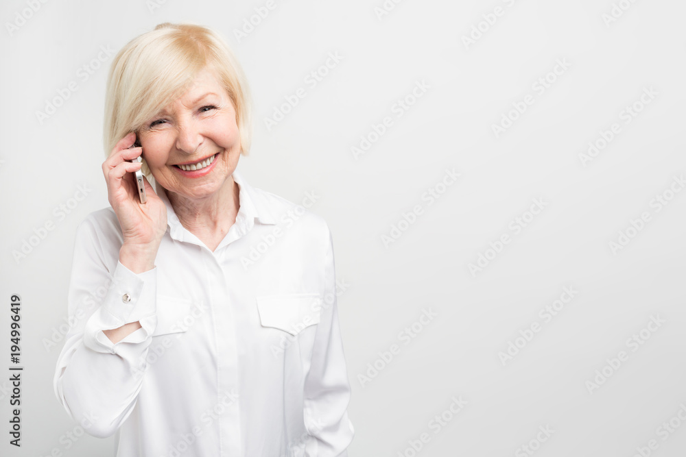 A picture of old lady using new phone. She likes to test it. This phone is her favourite one. Isolated on white background. A picture of old lady using new phone. She likes to test it. This phone is her favourite one. Isolated on white background.