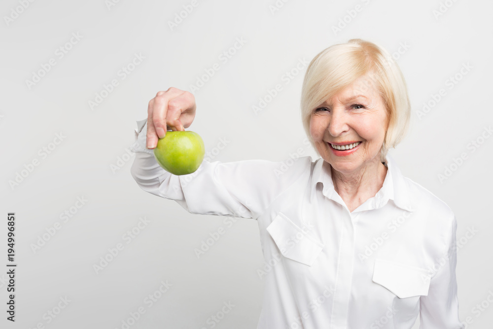 A beautiful mature woman holding a green apple in right hand. She likes to eat fruit. This is her choice. Isolated on white background. A beautiful mature woman holding a green apple in right hand. She likes to eat fruit. This is her choice. Isolated on white background.