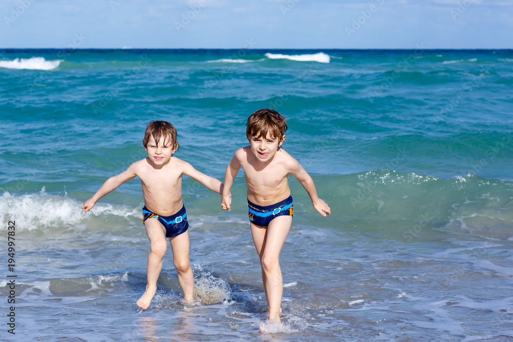 Two kid boys running on ocean beach. Little children having fun Two kid boys running on ocean beach. Little children having fun