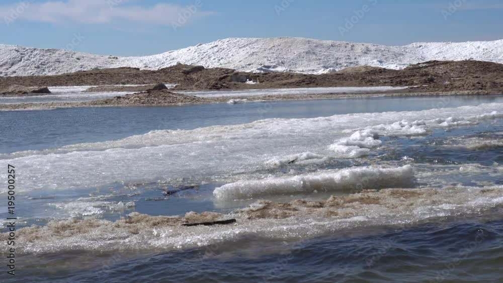 Edge of water with ice and snow along lake shore in winter with blue sky in the background Edge of water with ice and snow along lake shore in winter with blue sky in the background