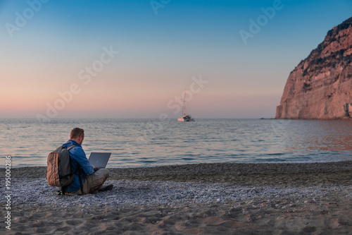 young man with laptop working on the beach. Freedom  remote work  freelancer  technology  internet  travel and vacation concepts