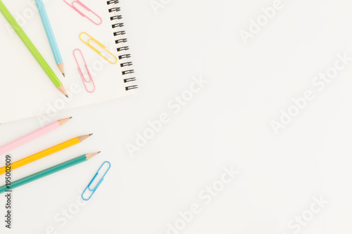 Flat lay photo of office desk with colorful pencil and paper clip,copy space top view