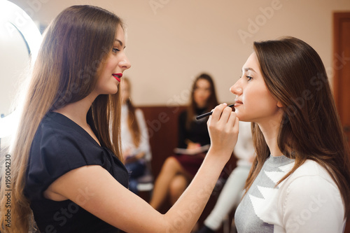 Makeup artist creating beautiful makeup for brunette model