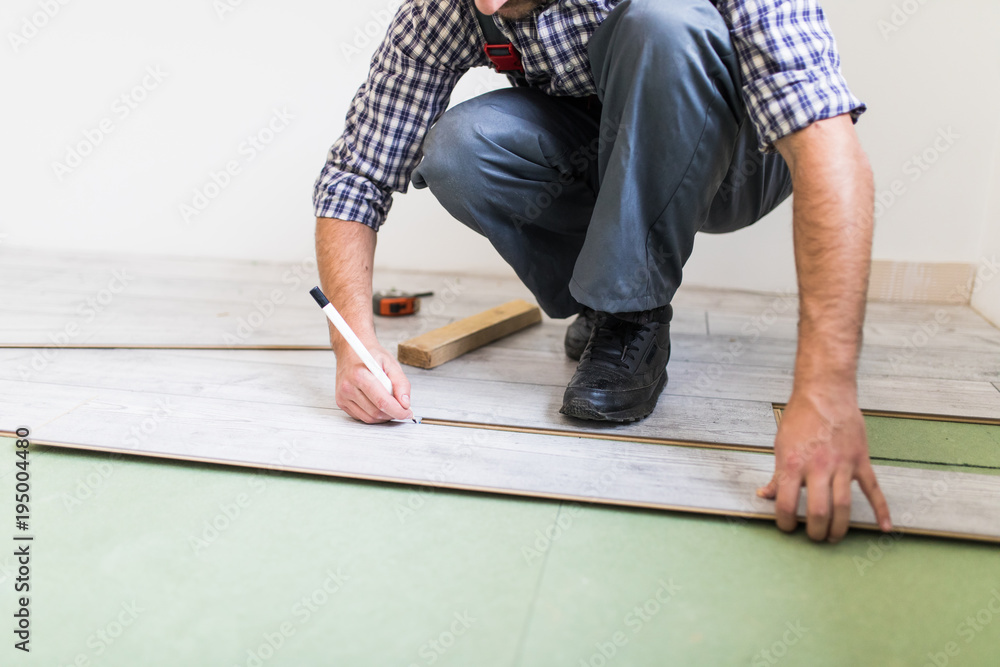 Close up man hands worker installing laminate flooring in the new room Close up man hands worker installing laminate flooring in the new room