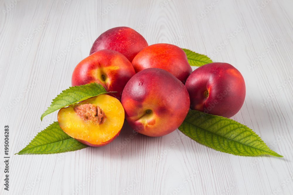 Peaches with leaves on a white wooden table Peaches with leaves on a white wooden table